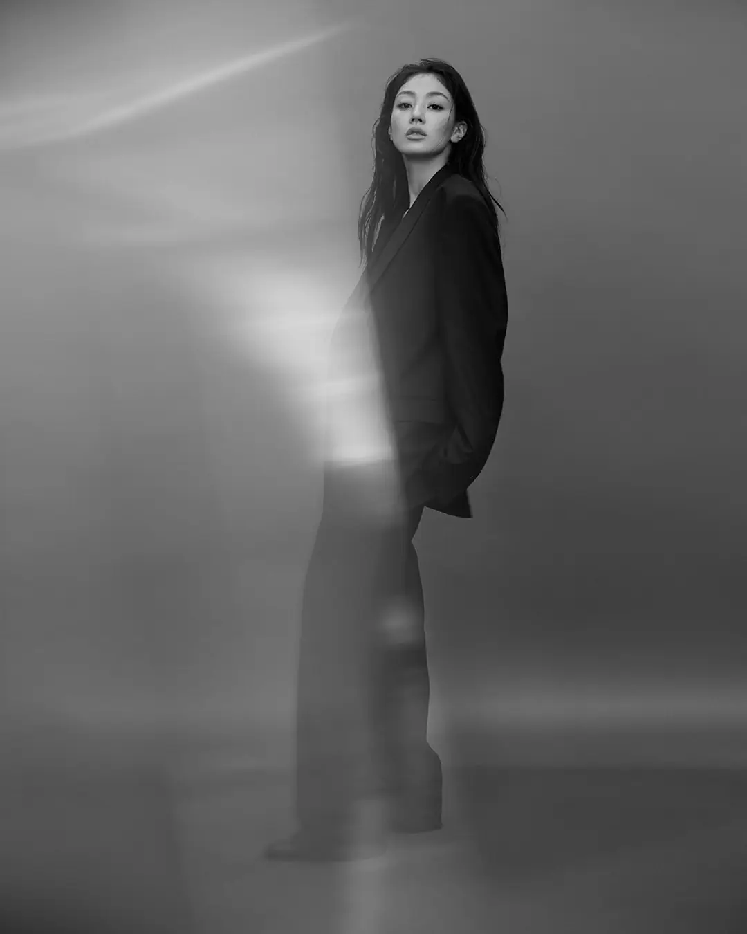 Jihyo in a black suit standing in soft, hazy light