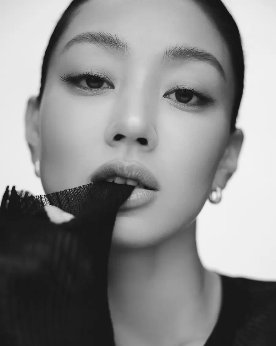 Black-and-white close-up of Jihyo holding black fabric to her lips