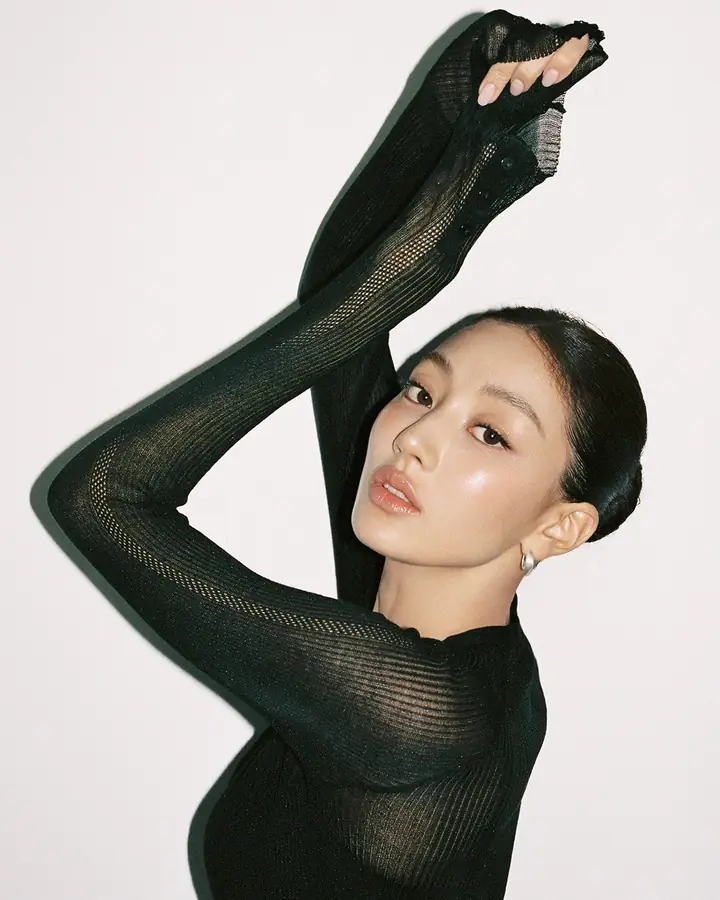 Jihyo with arms folded over her head in a black knit