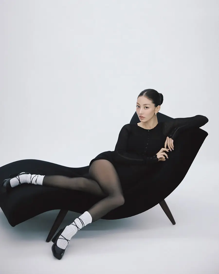 Jihyo reclining on a curved black chaise in knit, tights and white socks