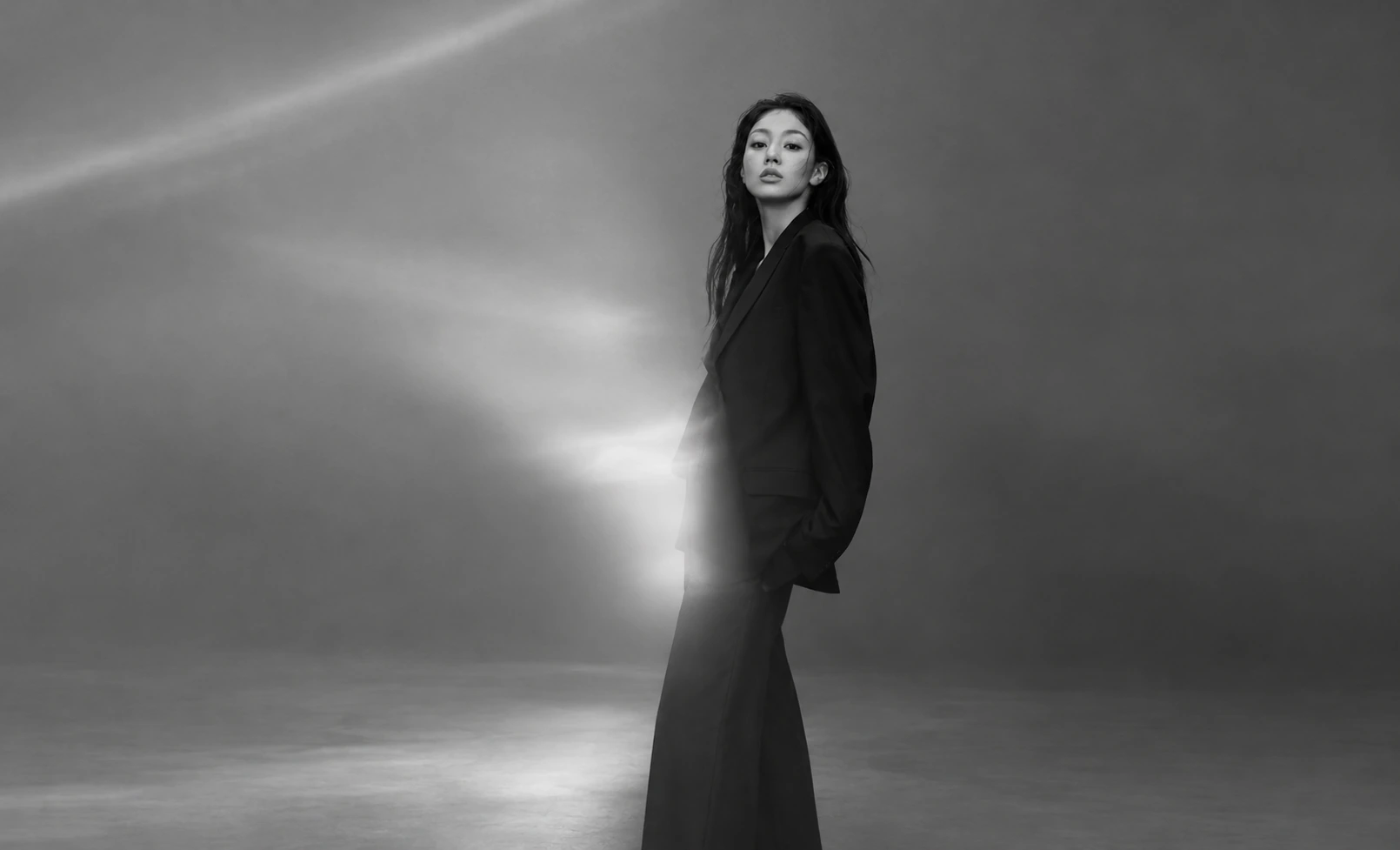 Jihyo in a black suit standing in a monochrome studio portrait